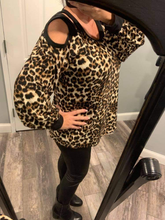 A long sleeve leopard print knit top with a round neck featuring a puff sleeve and a cut out detail.