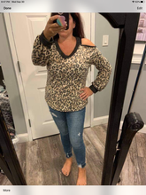 long sleeve leopard print knit top with a v-neck featuring a cold shoulder and a solid trim detail.