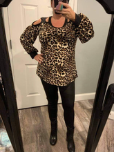 A long sleeve leopard print knit top with a round neck featuring a puff sleeve and a cut out detail.